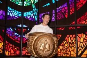 Adrian Gonzales, holding a giant model class ring in the Logsdon Chapel.